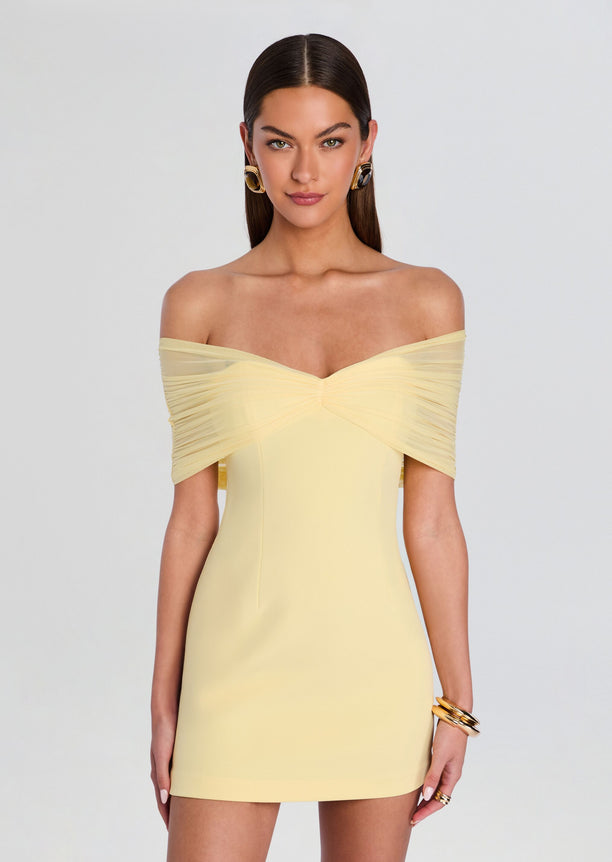 Portrait of a model wearing the pale yellow off-shoulder Jayne Mini Dress with a ruched sweetheart bodice