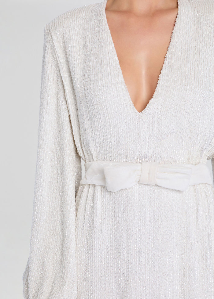 Close up of Lilai Sequin Dress showing a sparkling knit fabric and a deep V neckline with a white bow belt. media 2 of 5
