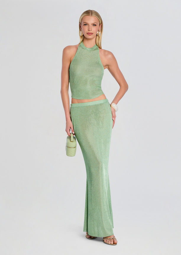 Model wearing mint green metallic knit halter top with matching skirt, holding a pale green mini bag.
