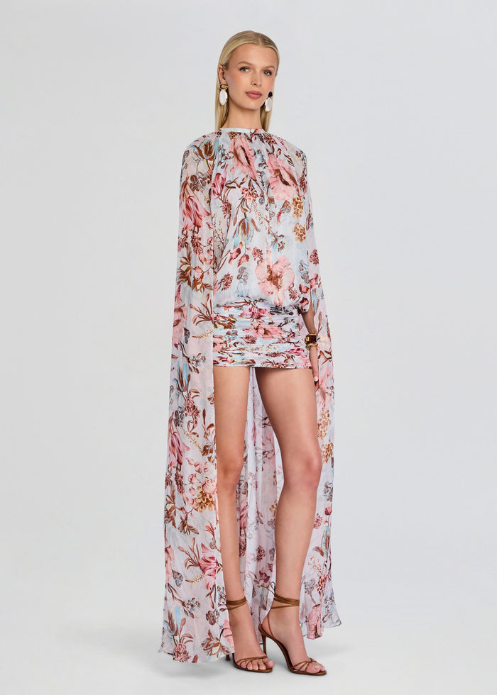 Full-length view of model wearing Ezra Ruched Cape Mini Dress with a sheer floral cape and pastel print media 3 of 5