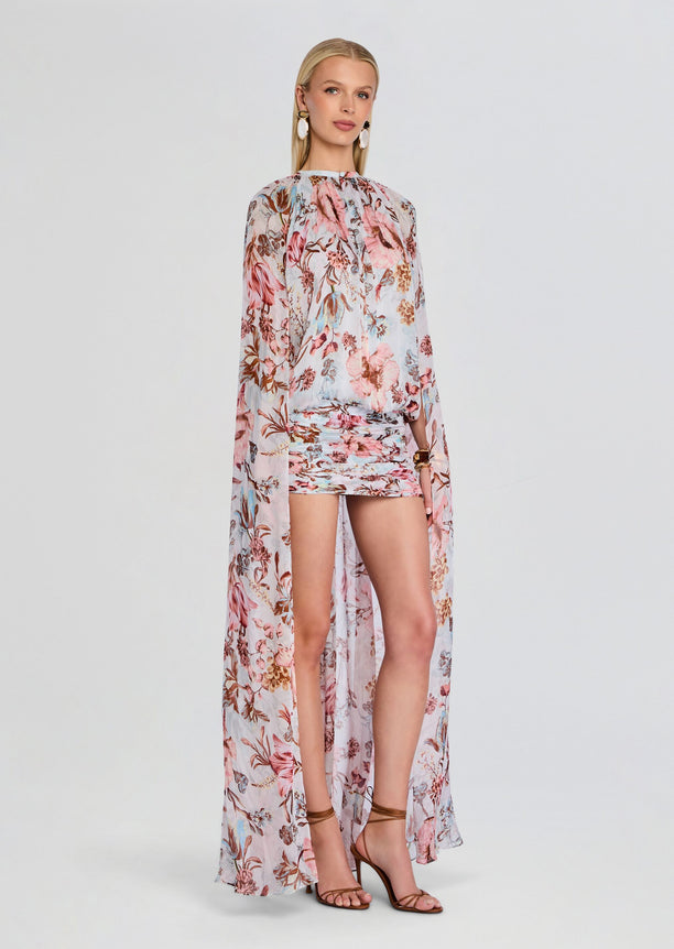 Full-length view of model wearing Ezra Ruched Cape Mini Dress with a sheer floral cape and pastel print