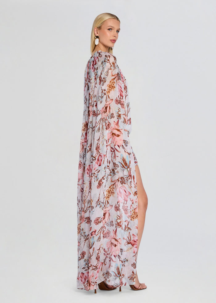 Profile view of model in Ezra Ruched Cape Mini Dress featuring a long sheer cape and floral print media 4 of 5