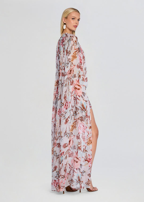 Profile view of model in Ezra Ruched Cape Mini Dress featuring a long sheer cape and floral print