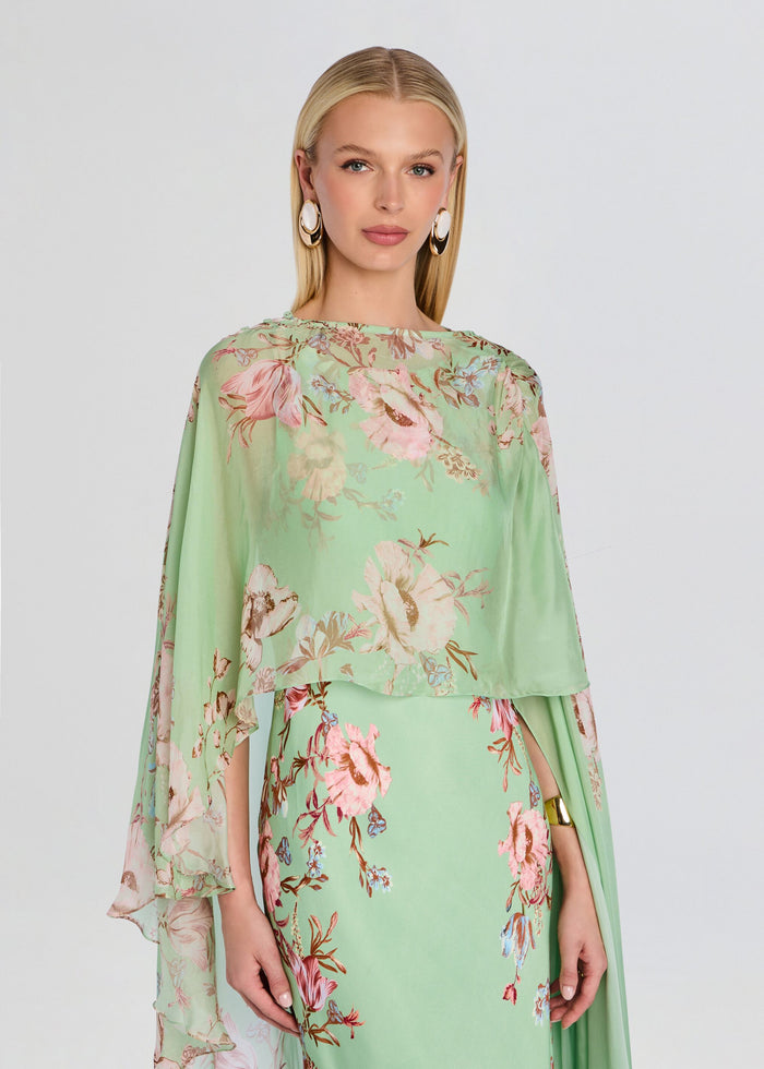 Model wearing mint green floral Ezra Ruched Cape with an oversized cape draped over shoulders. media 1 of 5