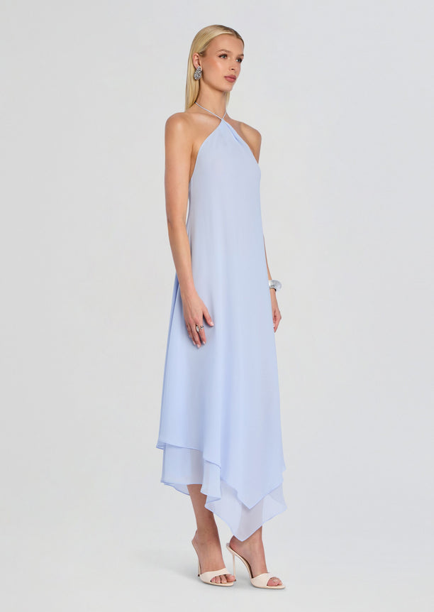 Sally Maxi Dress in light blue shown from the side with an asymmetric layered hem and nude heels.