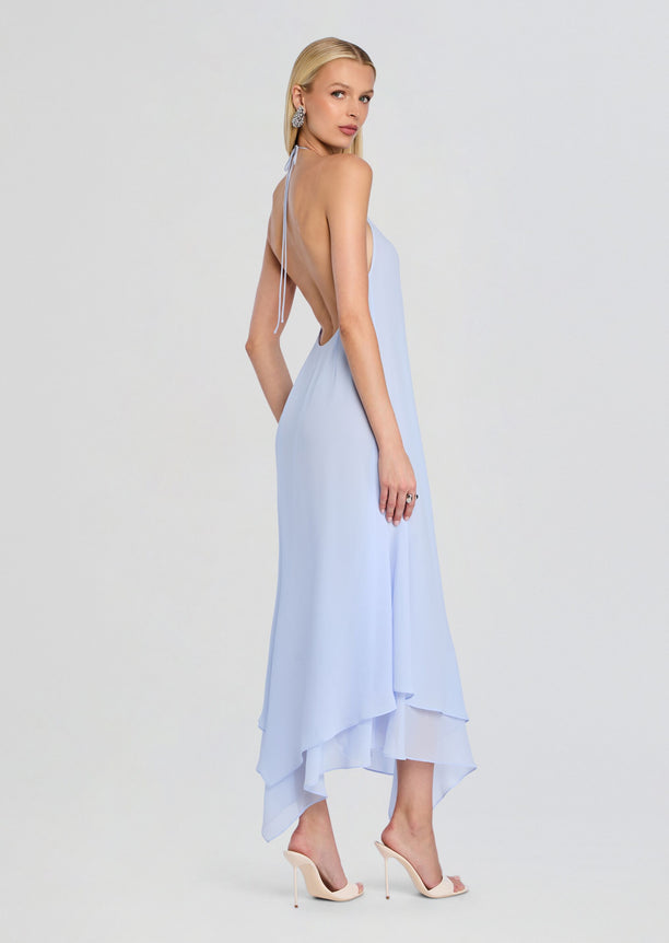 Side view of a model in a light blue Sally Maxi Dress with halter neck, open back, and a cascading layered hem