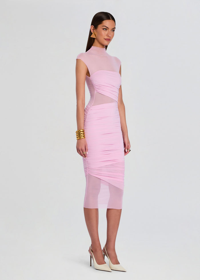 Three-quarter view of the model in the pink Tabitha dress, displaying side mesh panels and gathered ruching along the skirt. media 3 of 5