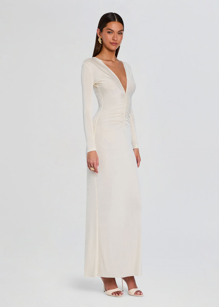 Side view of a model wearing the cream Ebony Maxi Dress with long sleeves and a slim silhouette. media 3 of 5