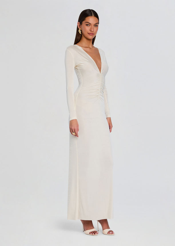 Side view of a model wearing the cream Ebony Maxi Dress with long sleeves and a slim silhouette.