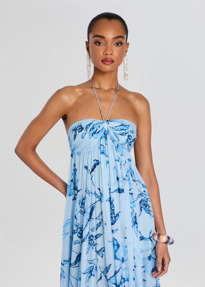 Model wearing a light blue flared dress with a blue floral print and a thin halter neck strap. media 5 of 5