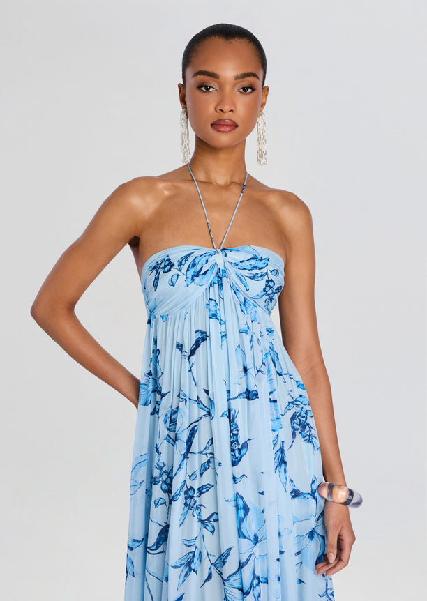 Model wearing a light blue flared dress with a blue floral print and a thin halter neck strap.