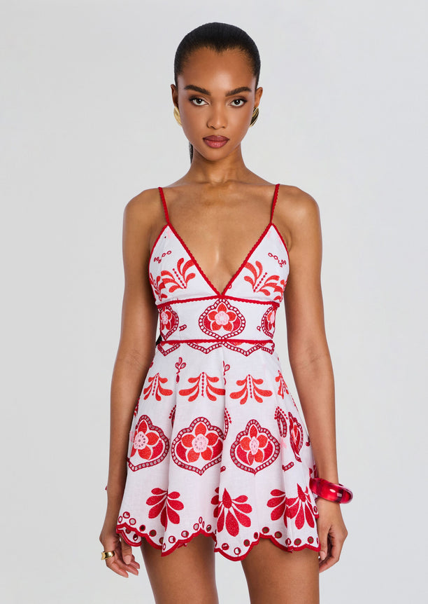 Front view of the Jela Short Dress with red embroidered pattern on white fabric and a flared mini hem.