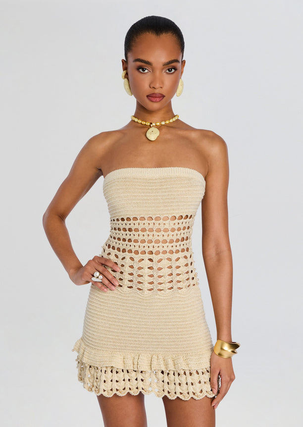 Front view of beige crochet strapless mini dress with textured bodice and scalloped hem worn with gold jewelry