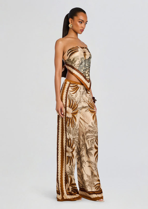 Full-length side view of model in the Alivia Silk Top with matching palm-leaf print wide-leg pants and scarf belt.