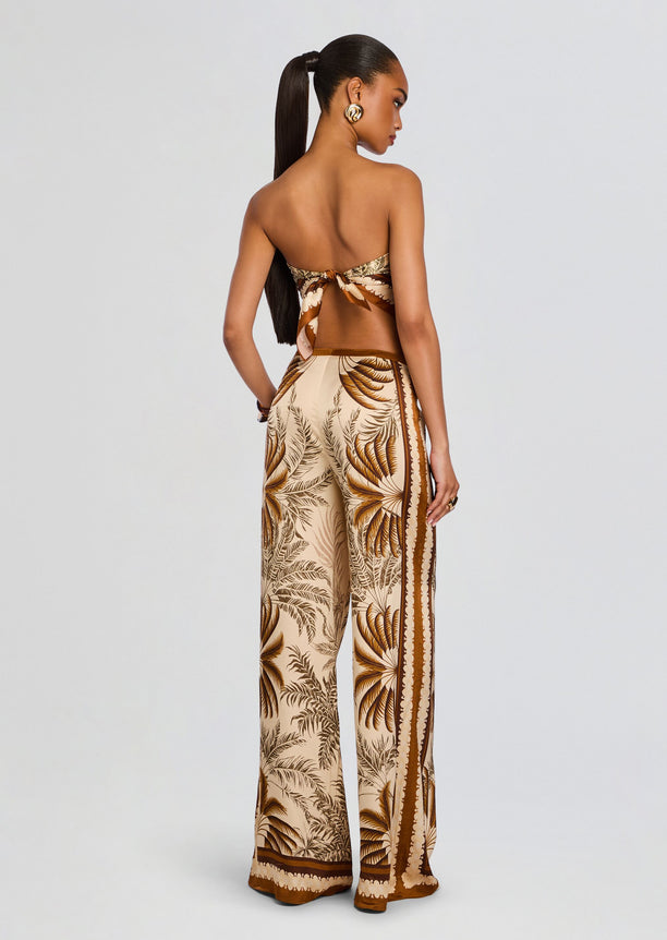 Back view of a model wearing Sunny Pant wide-leg tropical print pants with a tied-back top