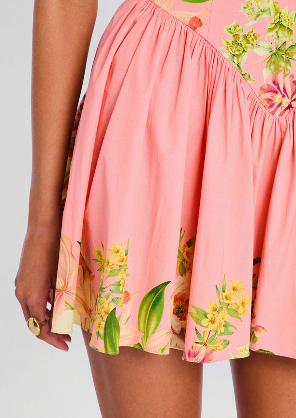 Close-up of the pink skirt with tropical floral border print along the hem.