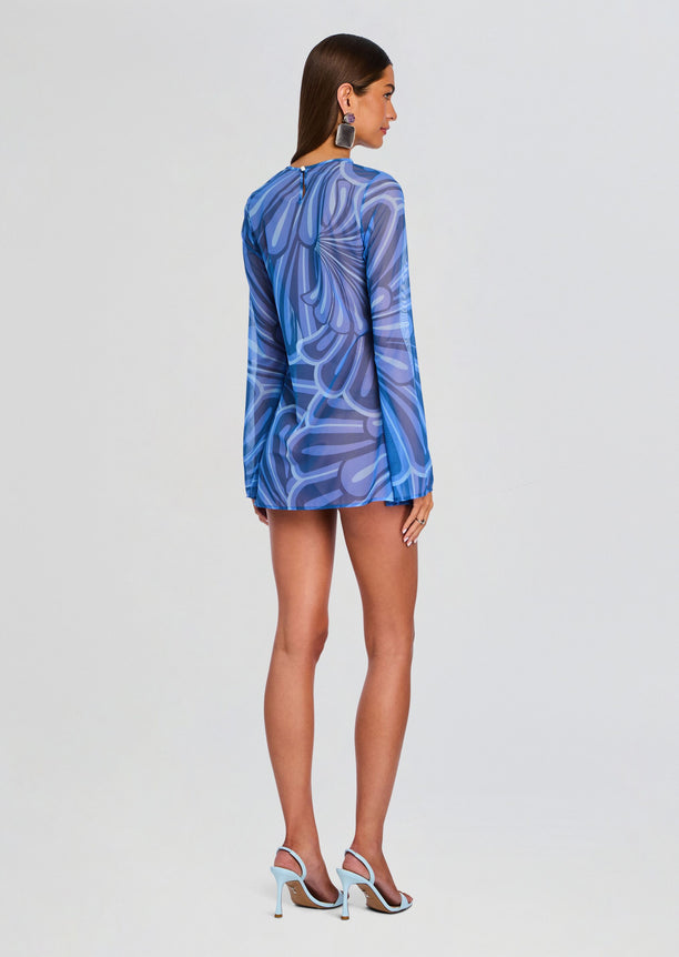 Back view of a model wearing the Catherine Mini Dress in blue abstract print with a short hem and light blue heels.