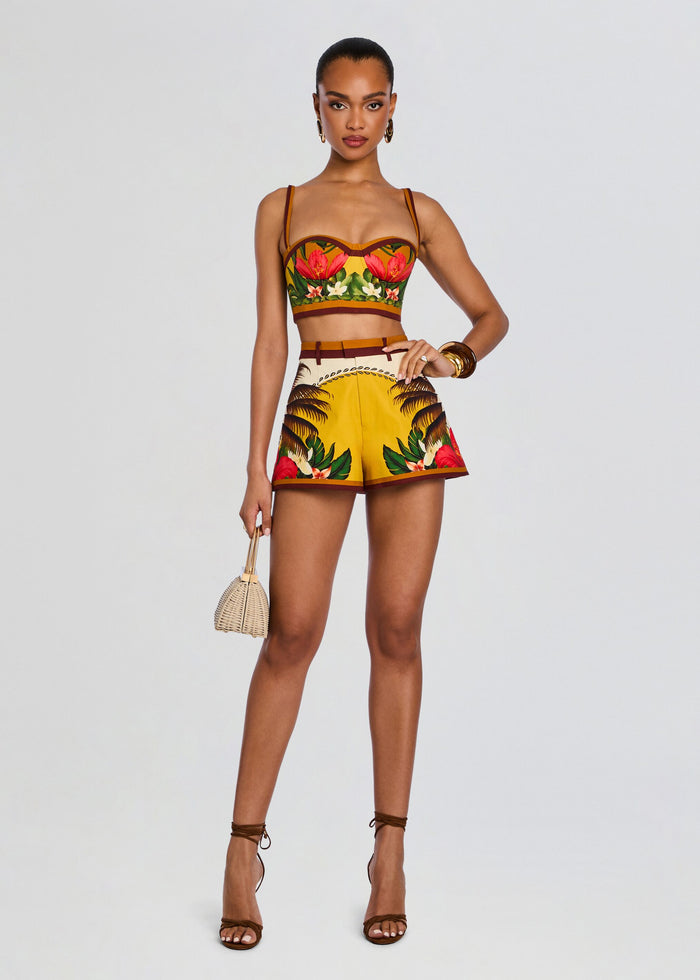 Model wearing a tropical floral bustier top with brown trim and matching palm leaf print shorts. media 2 of 5