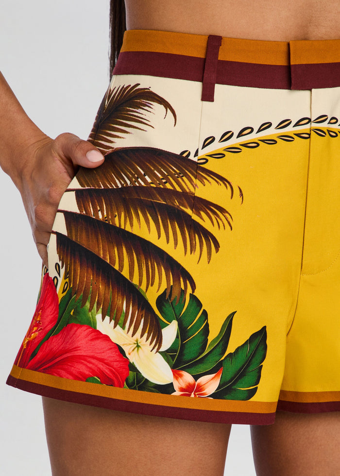 Close up of Tansie Short showing tropical palm leaf print on yellow fabric with brown trim. media 3 of 5
