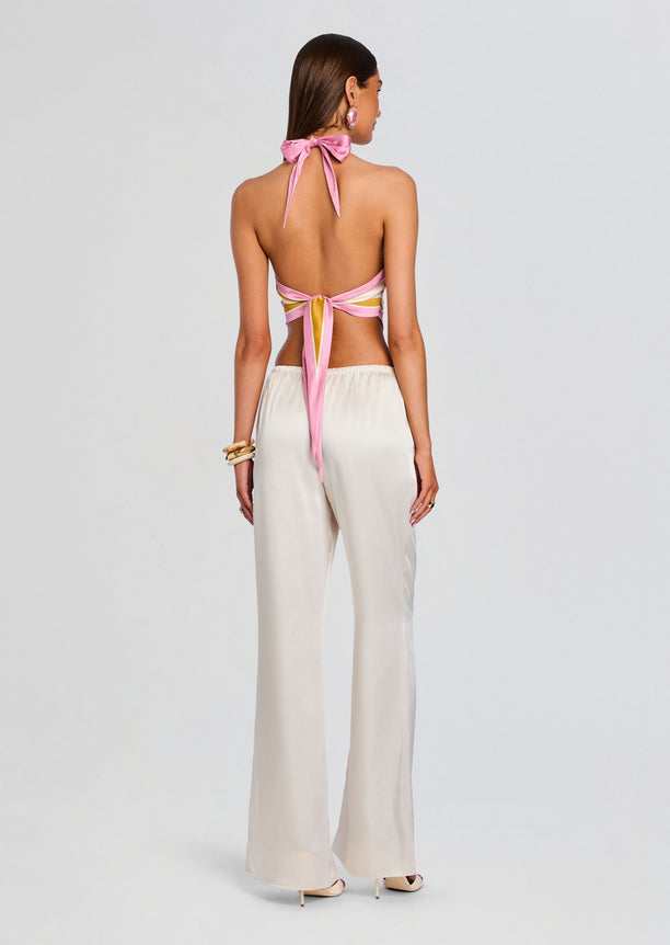 Back view of Jamie Silk Top with pink halter ties tied into a bow and cream wide-legged pants
