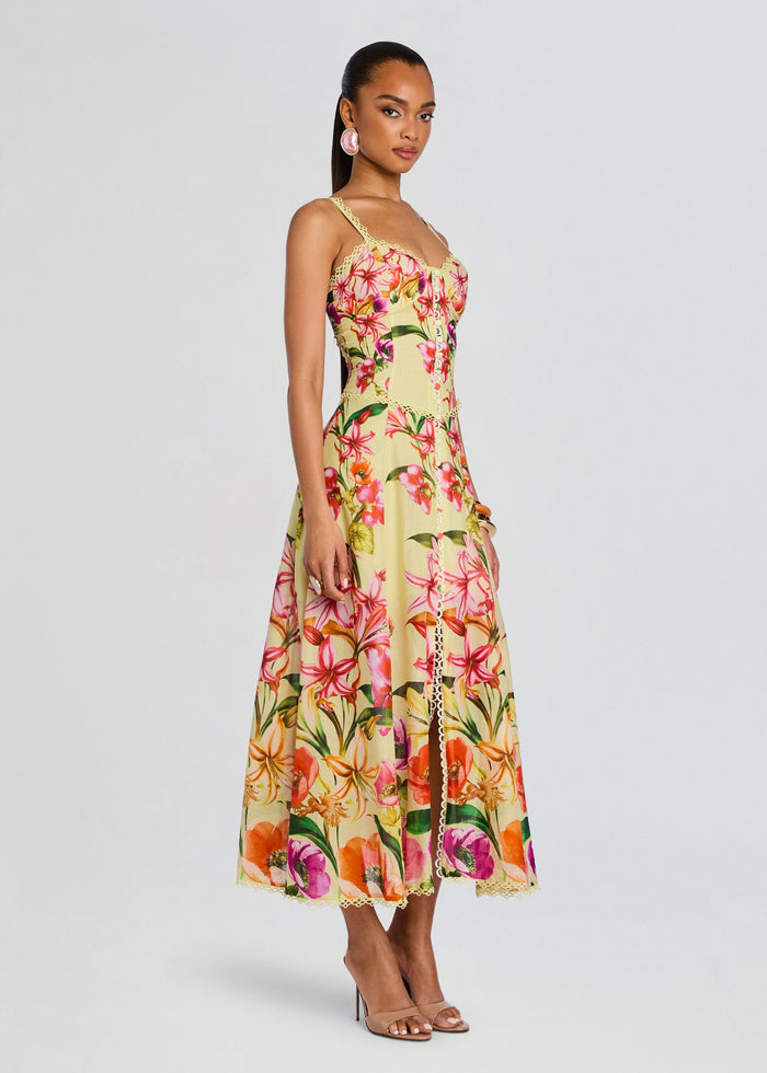 Full-length side view of a model wearing the Solara Long Dress in a yellow floral print with lace trim and thin straps. media 3 of 5