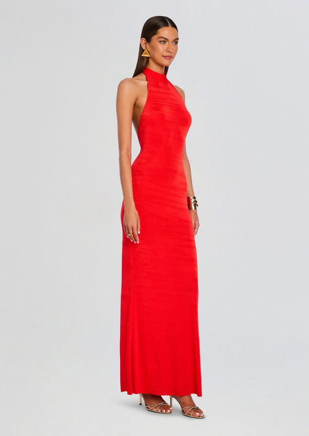 Full-length side view of a model wearing a red halter neck maxi dress