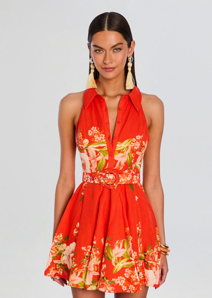Front view of a model wearing a red floral Hibi short dress with a belt buckle and large tassel earrings. media 5 of 5