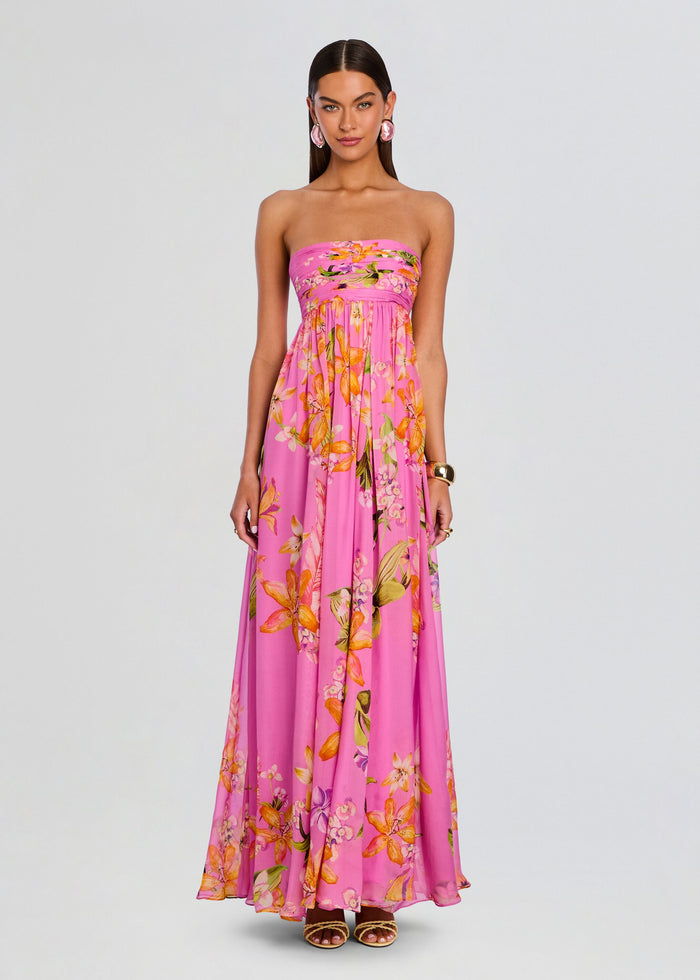 Model wearing a pink strapless floral Posy dress with a flowing long skirt and pink statement earrings media 1 of 5
