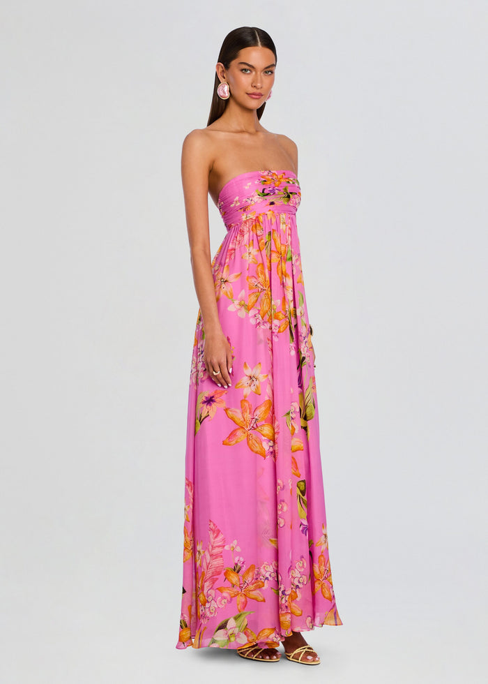 Full-length side view of a model in a pink floral Posy strapless dress with a flowing skirt and sandals media 3 of 5