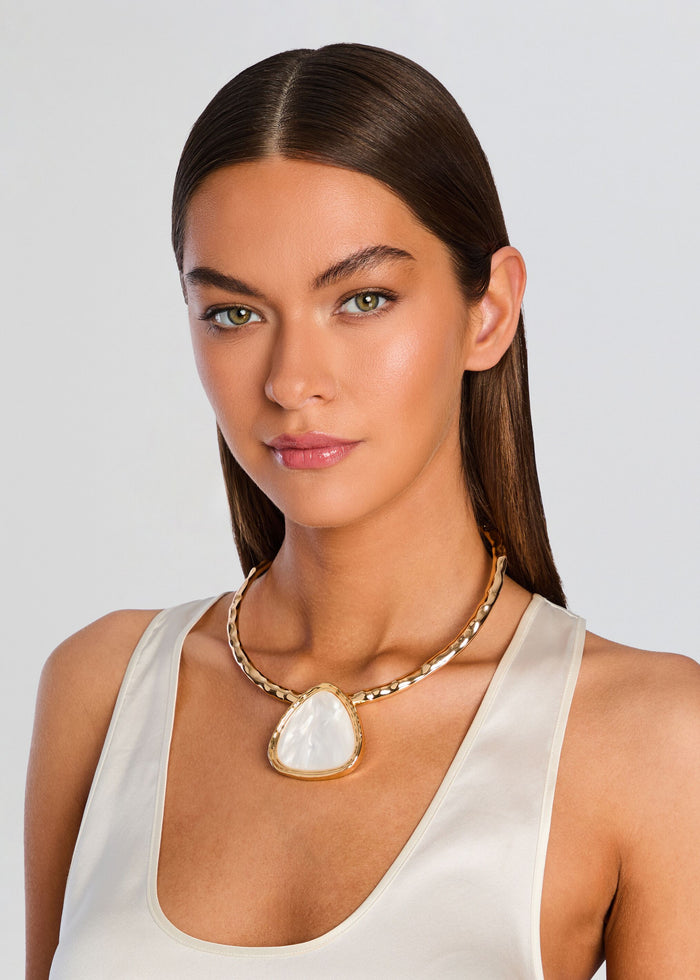 Model wearing a gold Sunset Necklace with a triangular pearlescent pendant. media 2 of 3