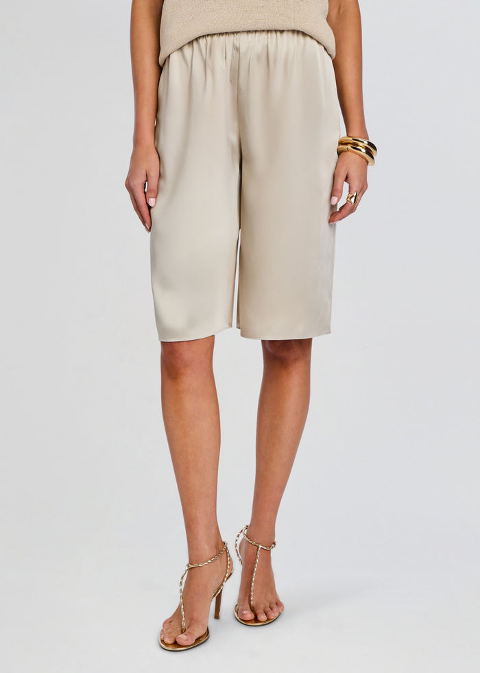 Beige satin Brice Bermuda Short on a model paired with a beige knit top and gold bangles. media 1 of 5