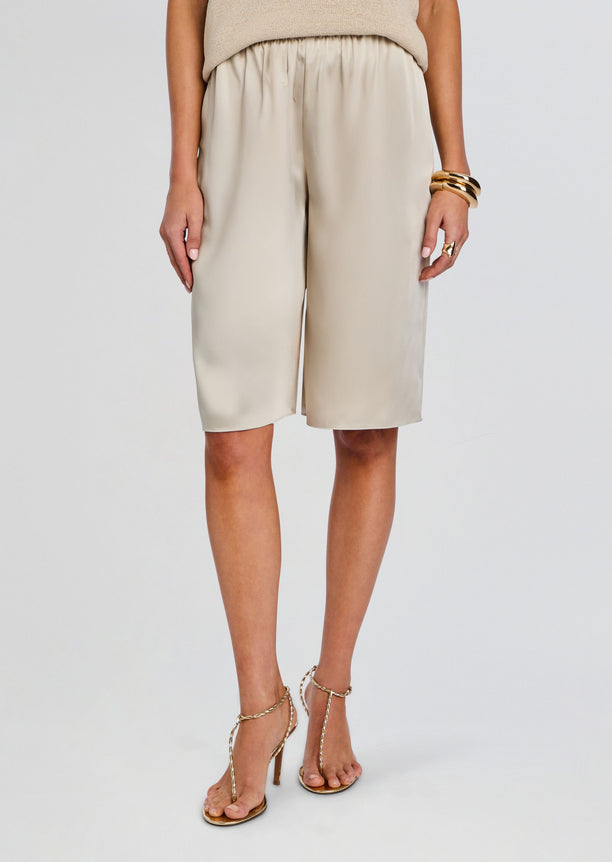 Beige satin Brice Bermuda Short on a model paired with a beige knit top and gold bangles.