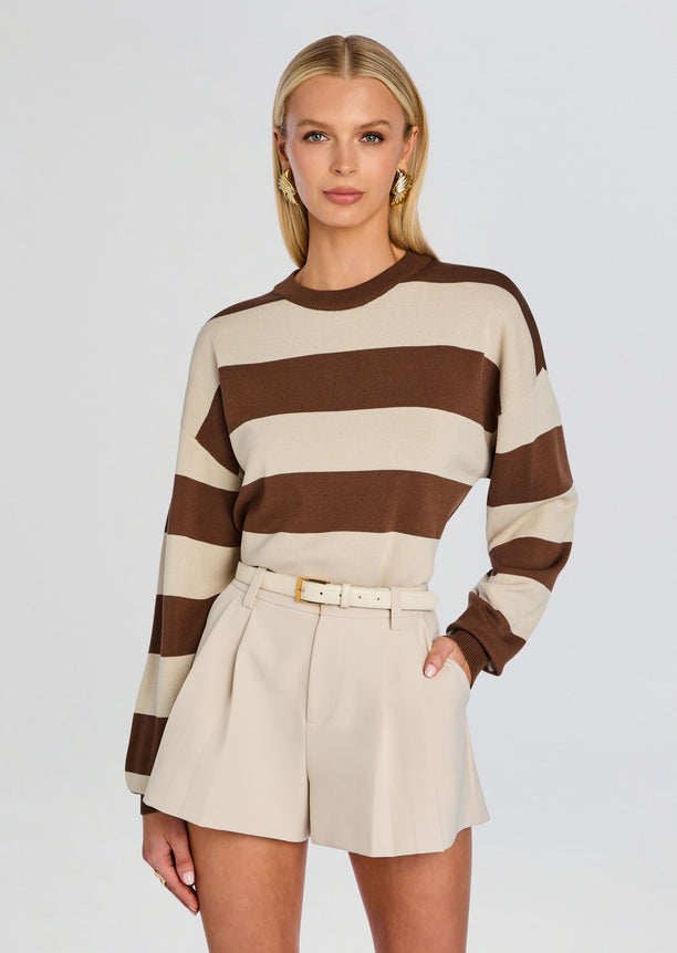 Model wearing Bryn Sweater in brown and beige wide stripes with cream tailored shorts.