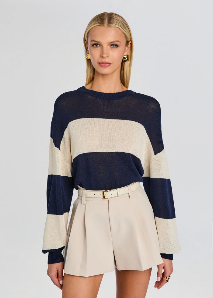 Model wearing a navy and cream striped Cassian Sweater with beige high waisted shorts and belt media 1 of 5