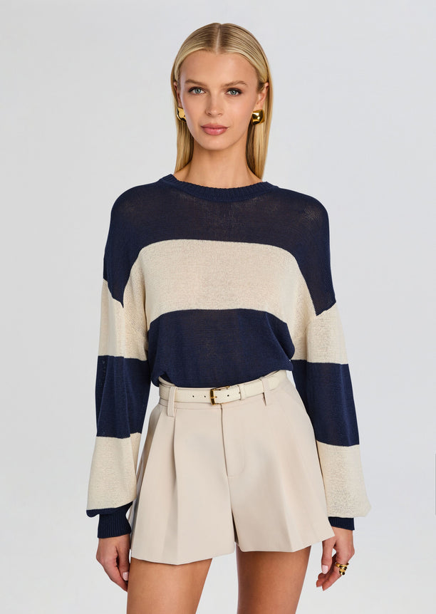 Model wearing a navy and cream striped Cassian Sweater with beige high waisted shorts and belt