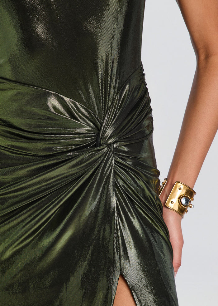 Close-up of a metallic olive green dress with a dramatic gathered twist detail at the waist and a side slit, worn by a model with a gold cuff bracelet. media 2 of 5