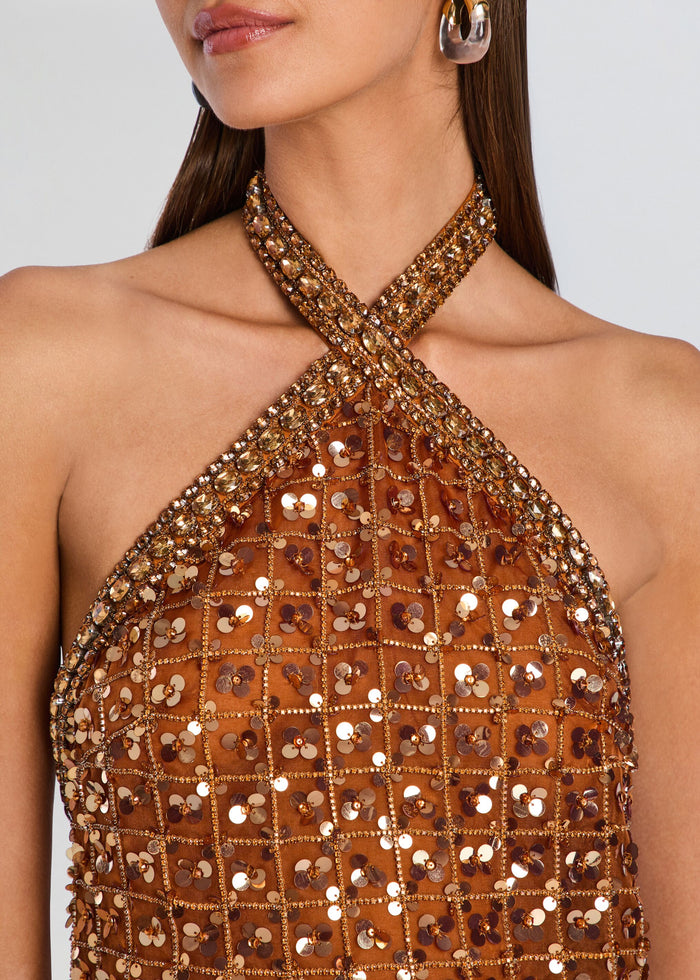 Close-up of a model wearing a halter-neck sequined top in a warm bronze-brown color with metallic gold sequins arranged in a grid pattern. media 2 of 5