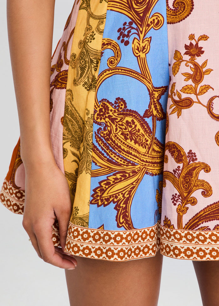 Close-up of a person wearing a patterned dress with a mix of yellow, blue, and pink colors. media 2 of 5