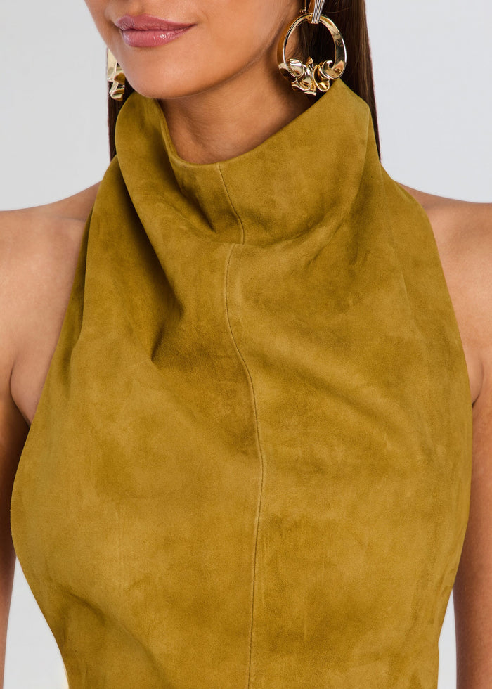 Close-up of a model wearing a mustard yellow suede halter top with a high gathered neckline and large gold hoop earrings against a light gray background. media 2 of 5