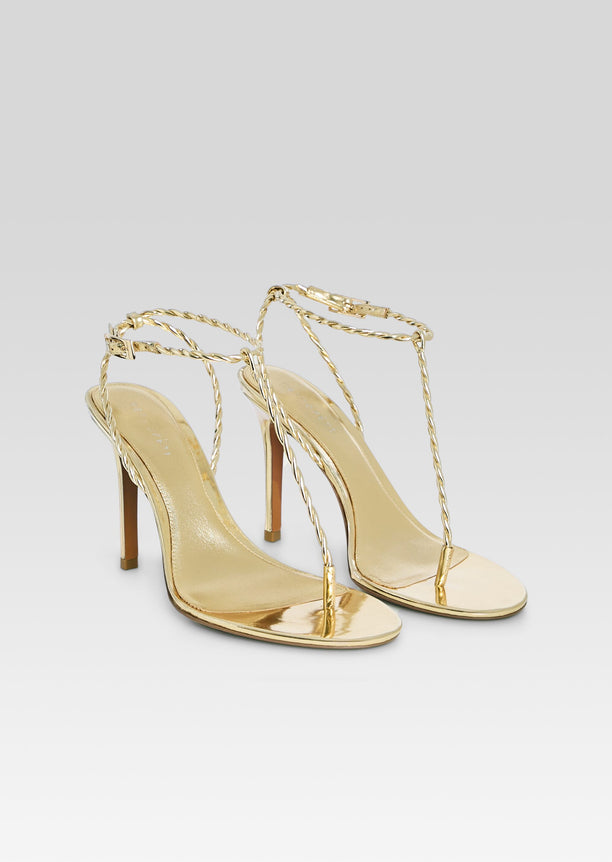 Pair of gold metallic Cleo sandals with braided ankle straps and high heels