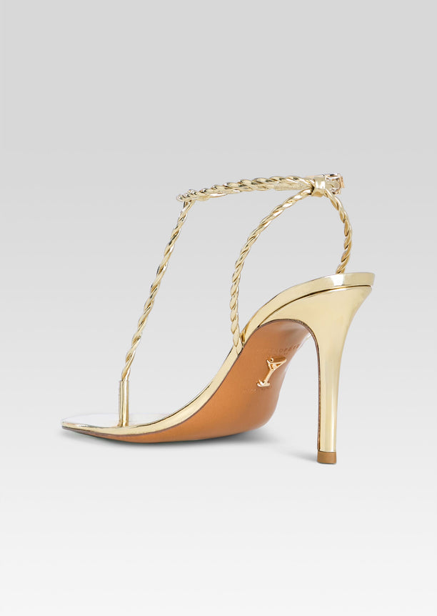 Golden Cleo sandal in side view with braided rope ankle strap and slender heel