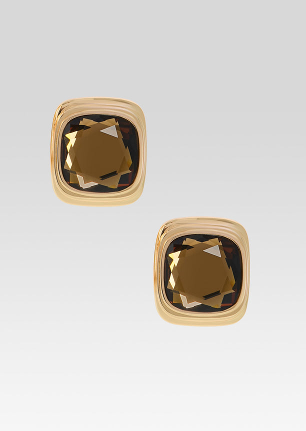Pair of square amber brown Clive Earrings in chunky gold-tone frames against a soft gradient backdrop.