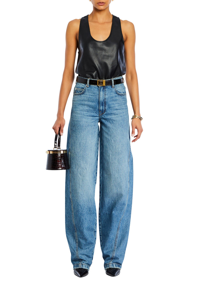 Model wearing a black faux leather tank top tucked into high waisted wide leg jeans with a belt and a small handbag. media 2 of 5