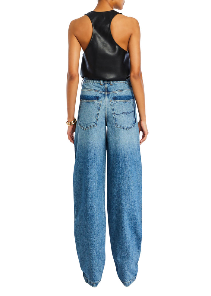 Back view of a model in a black faux leather tank top with high waisted blue jeans media 5 of 5