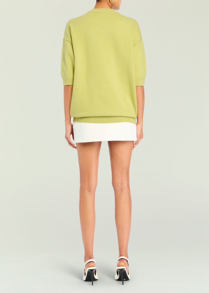 Back view of lime green Jacey Sweater with ribbed hem and cuffs, paired with a white mini skirt and heels media 4 of 5