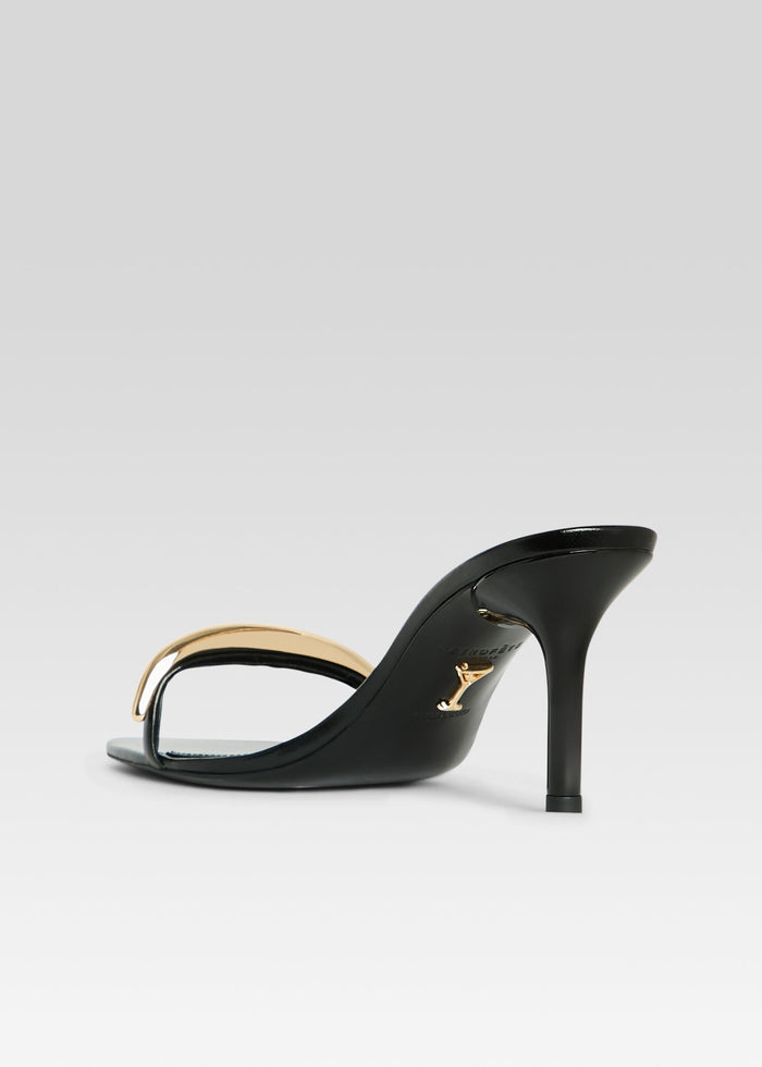 Side view of Karli Sandal featuring black leather upper and gold curved strap with slender heel media 5 of 5