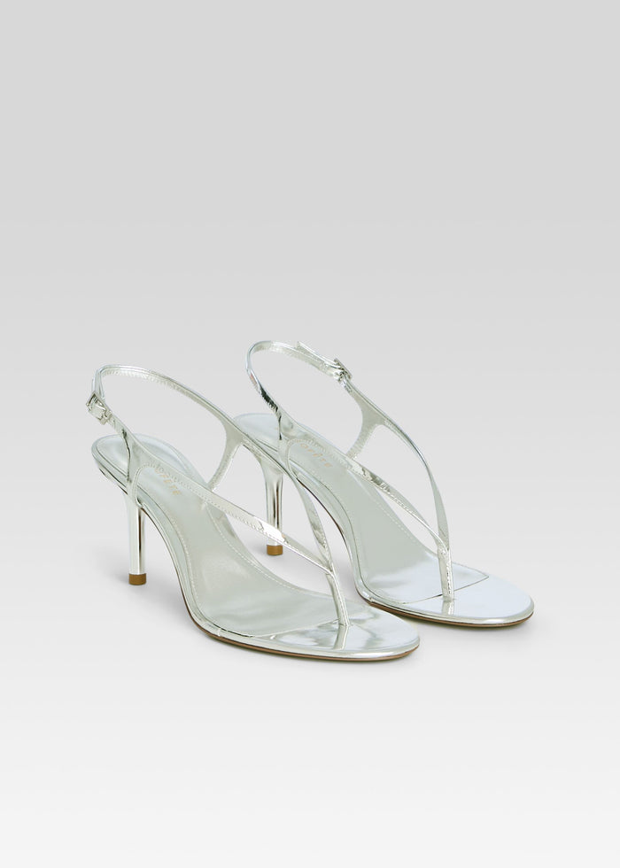 Pair of metallic silver Klotilde Sandals with slender straps and high heels on a light backdrop media 4 of 5