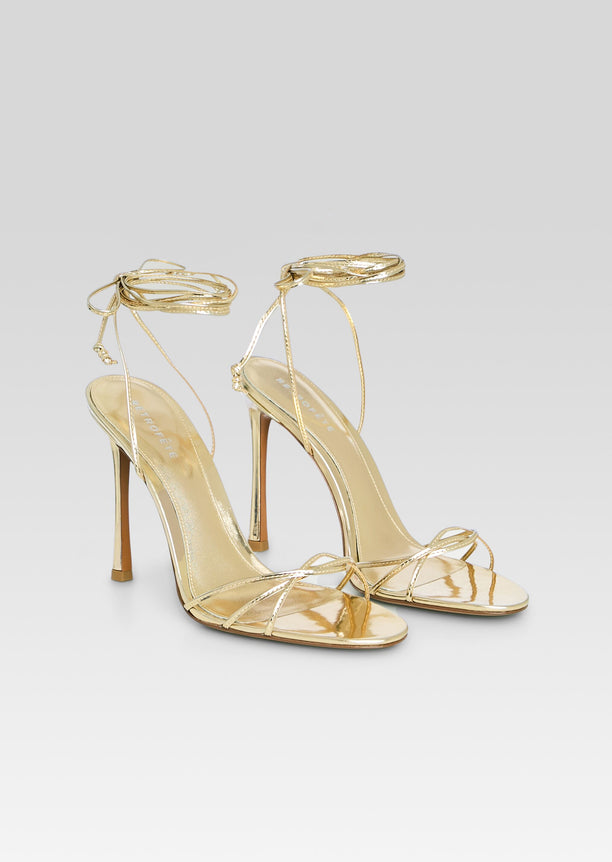 Two gold metallic Lucia Sandals with delicate toe straps and wraparound ankle ties posed together