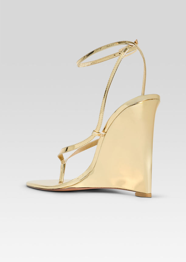 Gold metallic wedge sandal with delicate ankle wrap straps