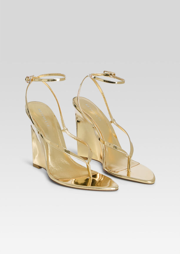 Namby Wedge pair of gold sandals with slender straps displayed on a light backdrop